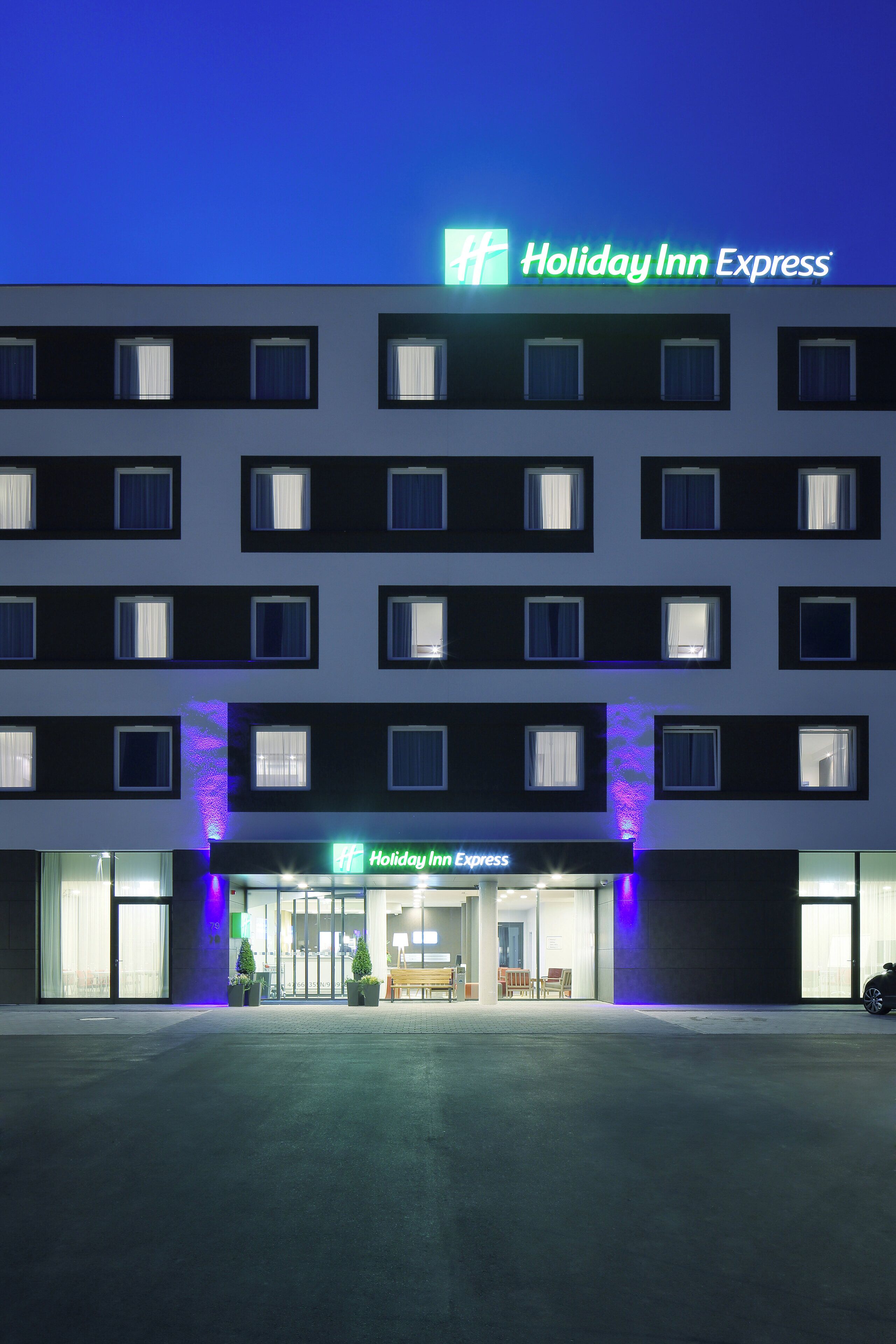 Un hotel Holiday Inn Express con una fachada moderna, múltiples ventanas y una entrada bien iluminada.