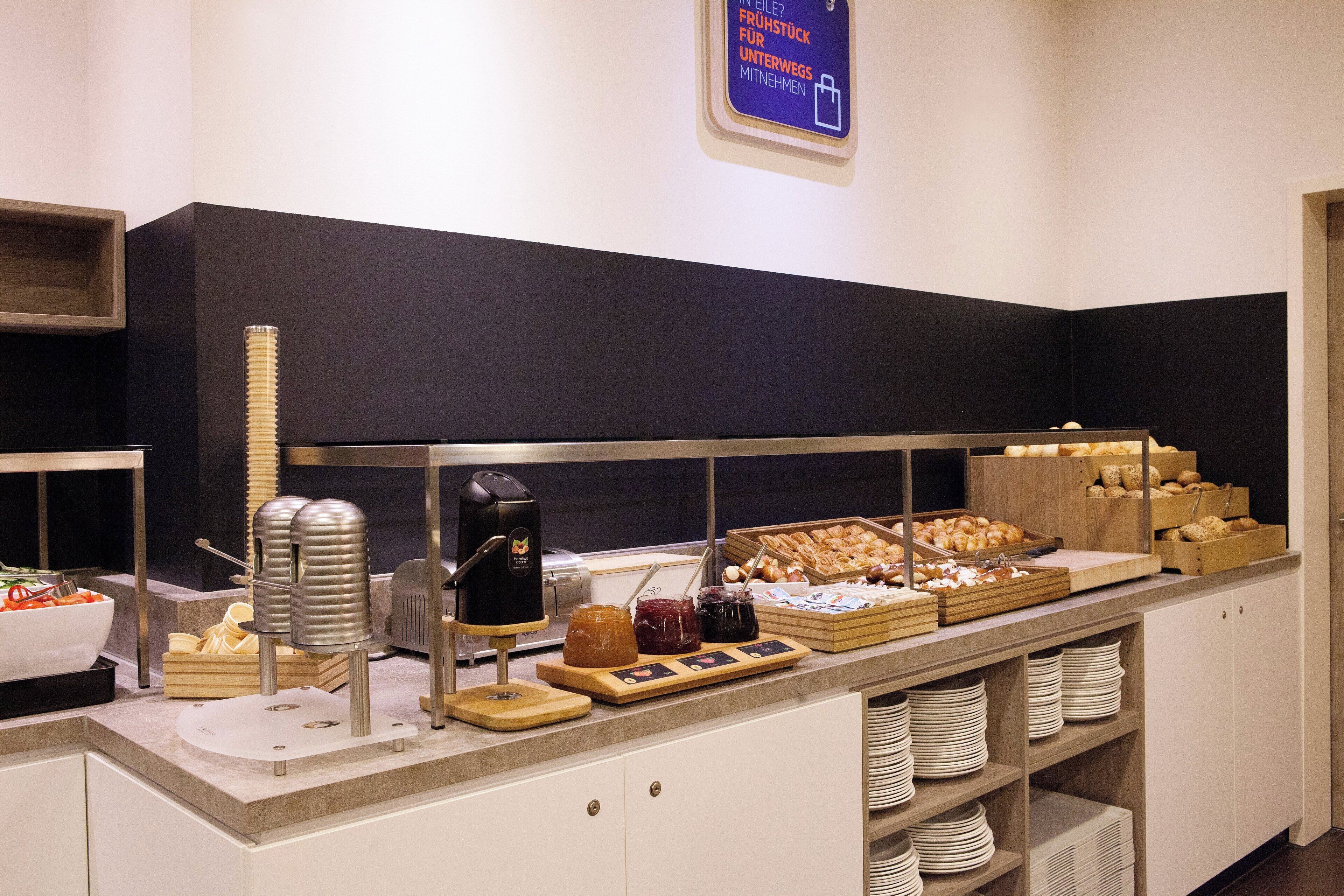 Un buffet proposant divers plats, une machine à café et un panneau indiquant un panier de fruits à la disposition des clients.