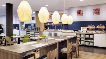 A modern cafe with wooden tables, chairs, and hanging pendant lights.