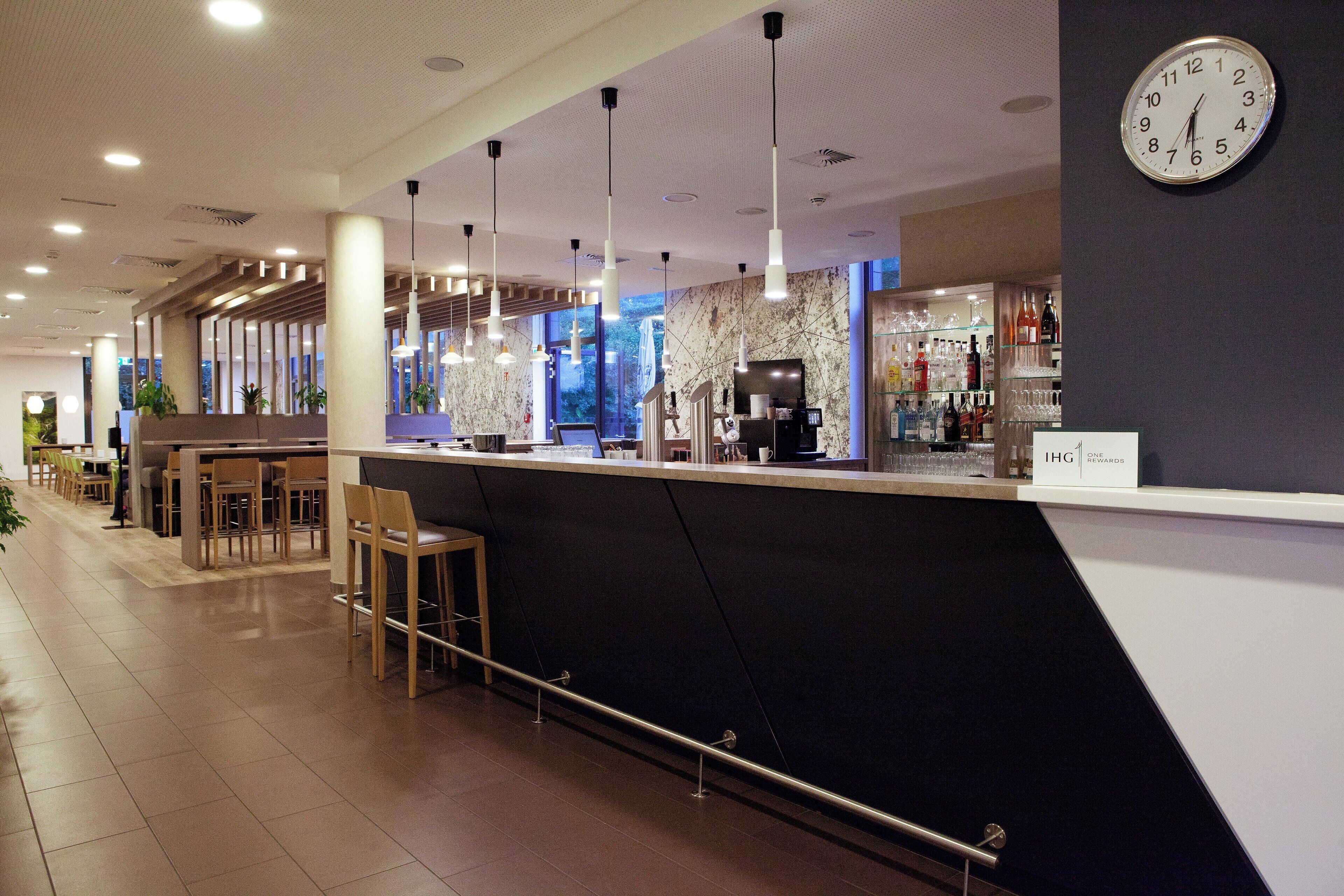 Un espace bar moderne avec un comptoir, des sièges et une horloge au mur.