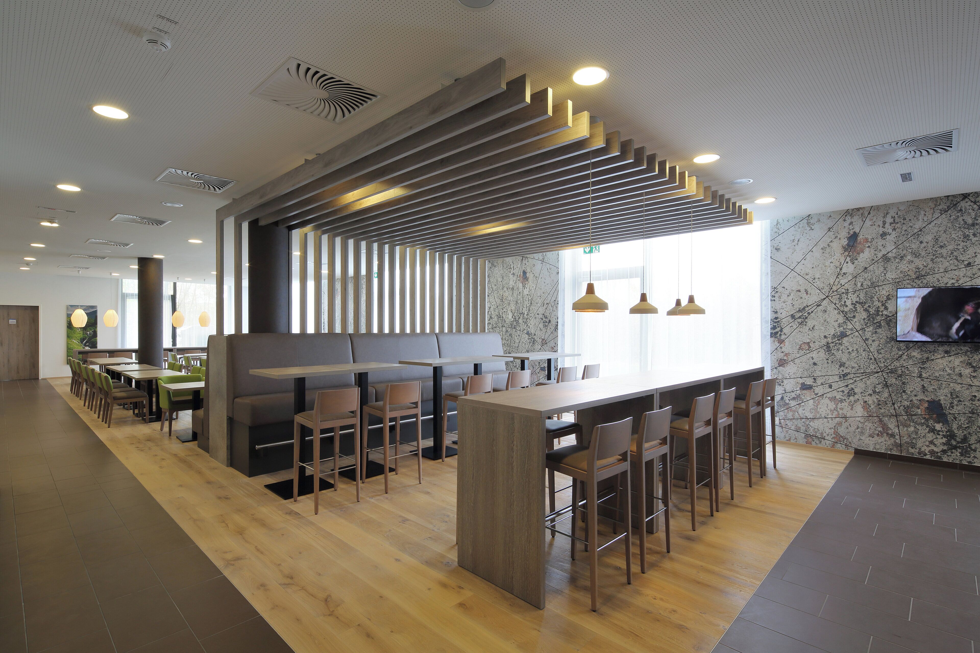 A modern restaurant interior with wooden flooring, a central bar area, and seating arrangements.