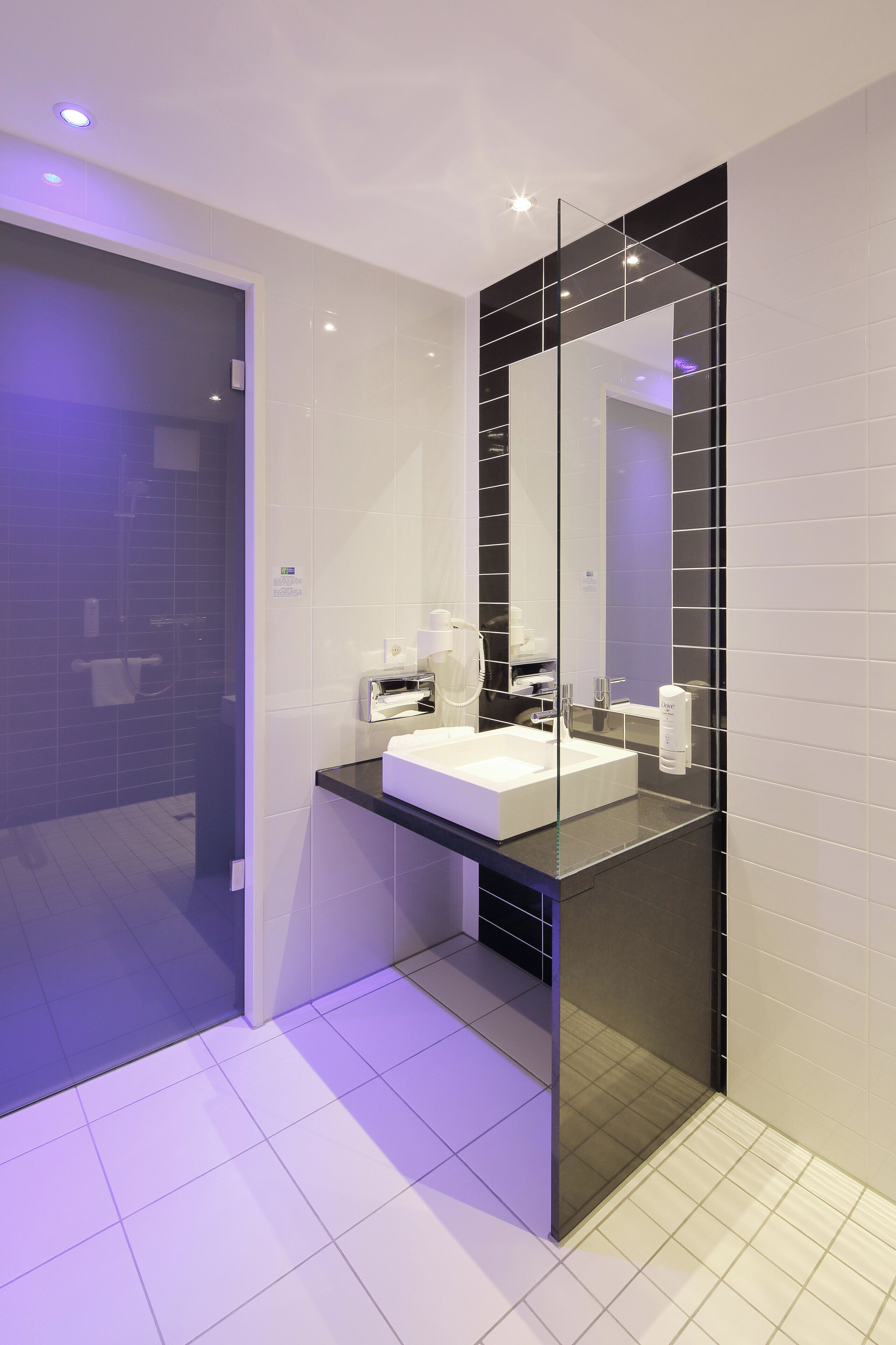 A modern bathroom with a large mirror, white sink, and black countertop.