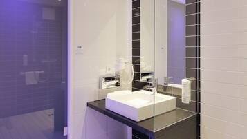 A modern bathroom with a large mirror, white sink, and black countertop.