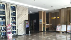 Een moderne hotellobby met een digitaal informatiepunt, een receptiebalie en een schone, gepolijste vloer.