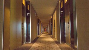 A long, narrow hotel corridor with doors on both sides, a patterned carpet, and a ceiling with recessed lighting. - Ibis Changzhou Lihua Hotel (Changzhou)