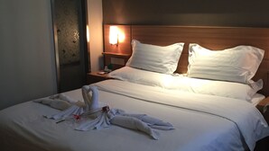 Een hotelkamer met een net opgemaakt bed, een hoofdeinde met een lamp en een schilderij aan de muur.