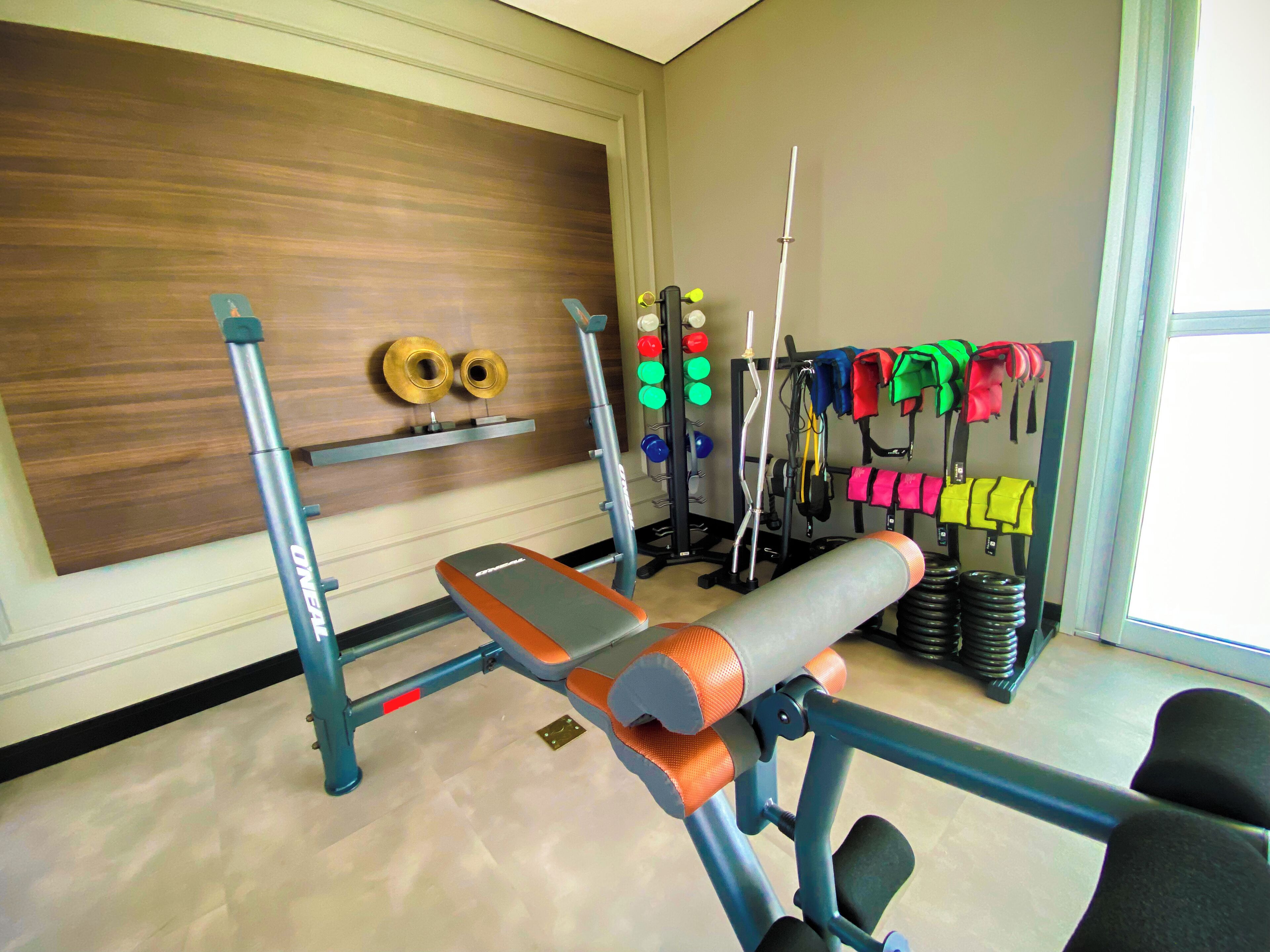 Une salle de sport équipée de matériel d’exercice, d’un banc et d’accessoires pour la musculation.