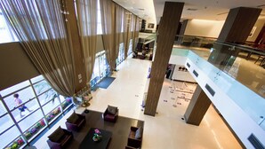 A spacious lobby with high ceilings, large windows, and a central seating area with sofas and tables. - Hotel Rainha do Brasil (Aparecida)