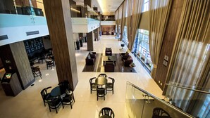 A spacious lobby with multiple seating areas, a staircase, and large windows allowing natural light. - Hotel Rainha do Brasil (Aparecida)