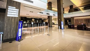 A spacious lobby with a reception desk, directional signage, and a clean, modern design. - Hotel Rainha do Brasil (Aparecida)