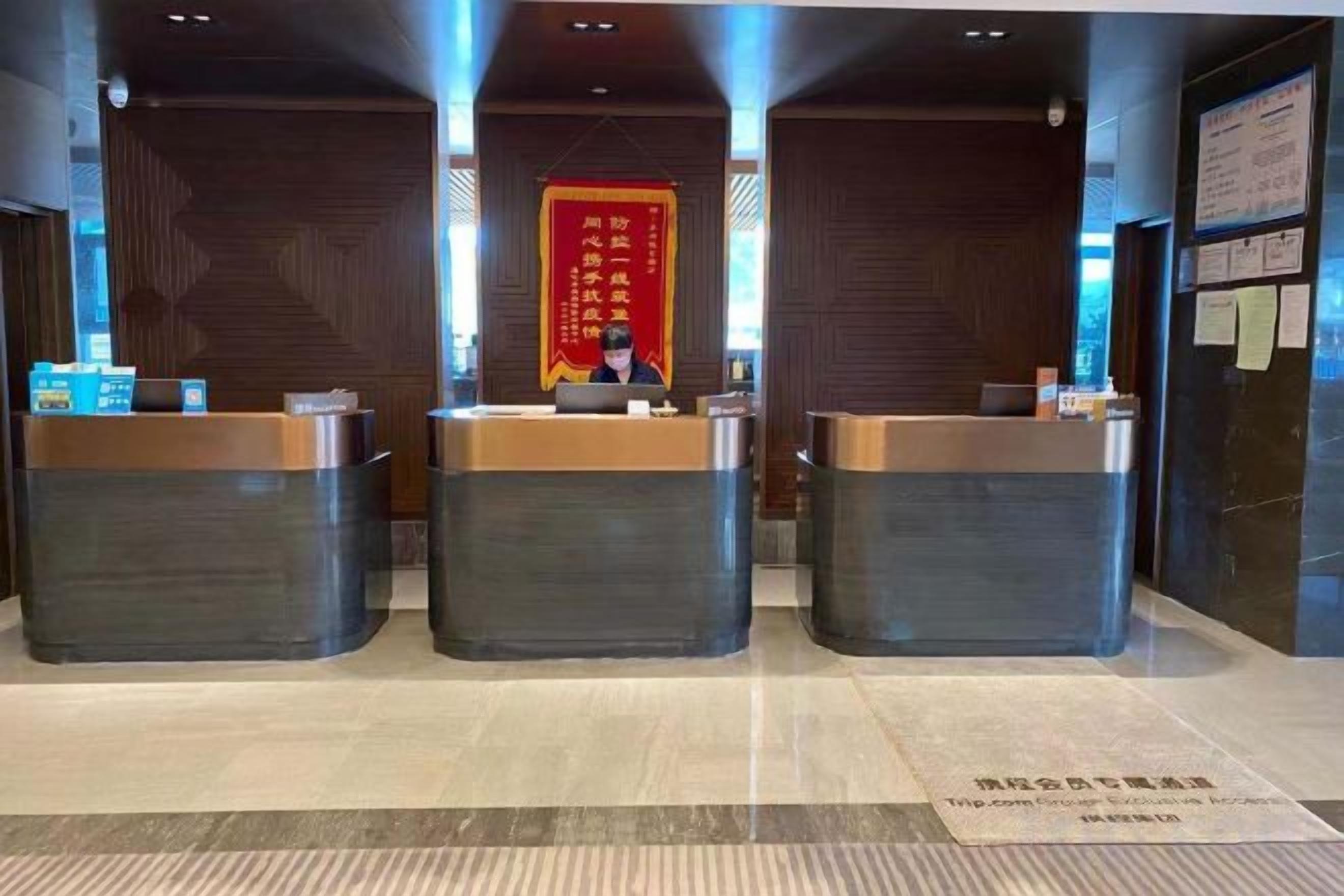A reception area with three counters, a red banner with Chinese characters, and a sign with text on the wall.