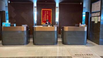 A reception area with three counters, a red banner with Chinese characters, and a sign with text on the wall.