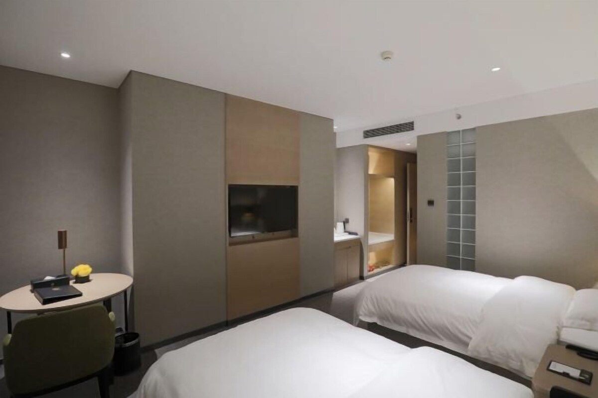 Una habitación de hotel con dos camas, un escritorio, una silla, un televisor y un baño.