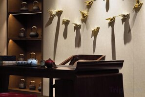 A room with a wooden desk, shelves with teapots, and wall-mounted hooks. - Eastern Holiday Hotel (Tonghua)