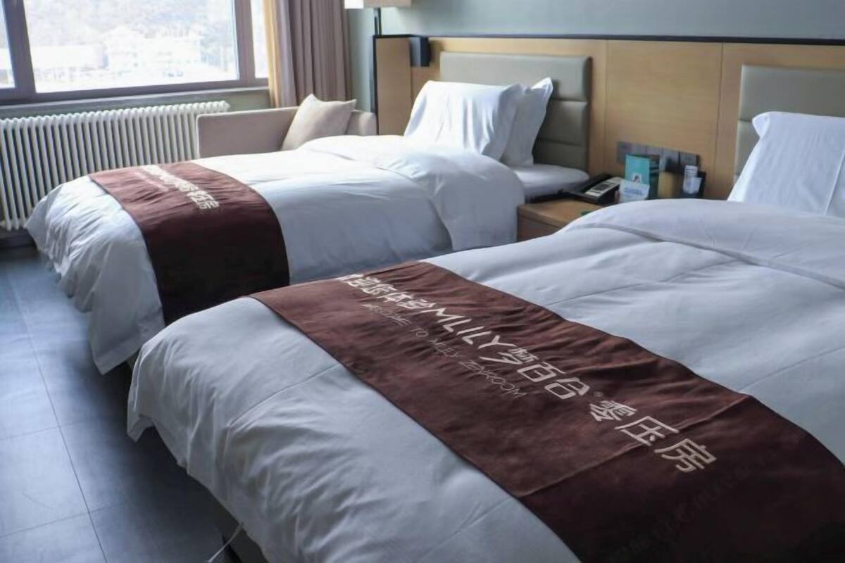 Habitación de hotel con dos camas, una mesita de noche, una ventana y un radiador.