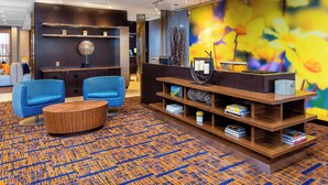 Een moderne lobby met blauwe stoelen, een houten salontafel en een kleurrijk tapijt.