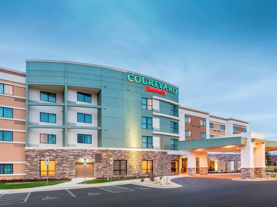 Un hotel Courtyard Marriott con un diseño moderno, varios pisos y una zona de entrada cubierta.