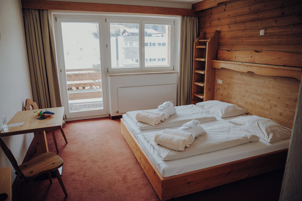 A wooden room with a bed, a desk, and a chair.