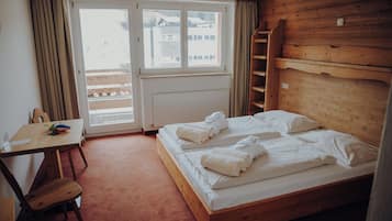 Een houten kamer met een bed, een bureau en een stoel.