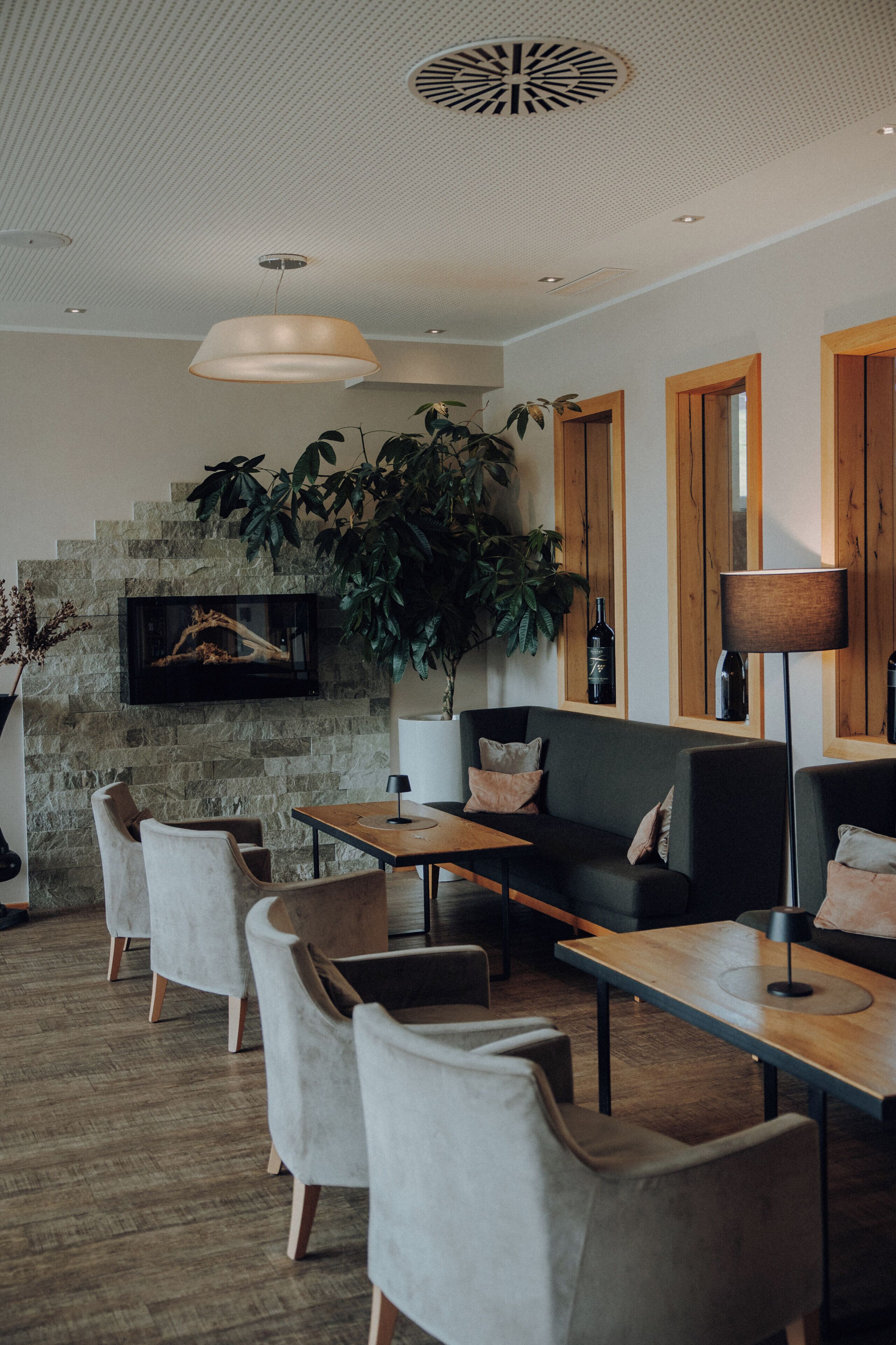Un intérieur moderne avec un mur en pierre, une grande plante, un téléviseur à écran plat et une table à manger en bois.