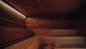 A sauna room with wooden benches and benches, a wooden floor, and a sloped ceiling. - alpenhotel Kaiserfels (Sankt Johann in Tirol)