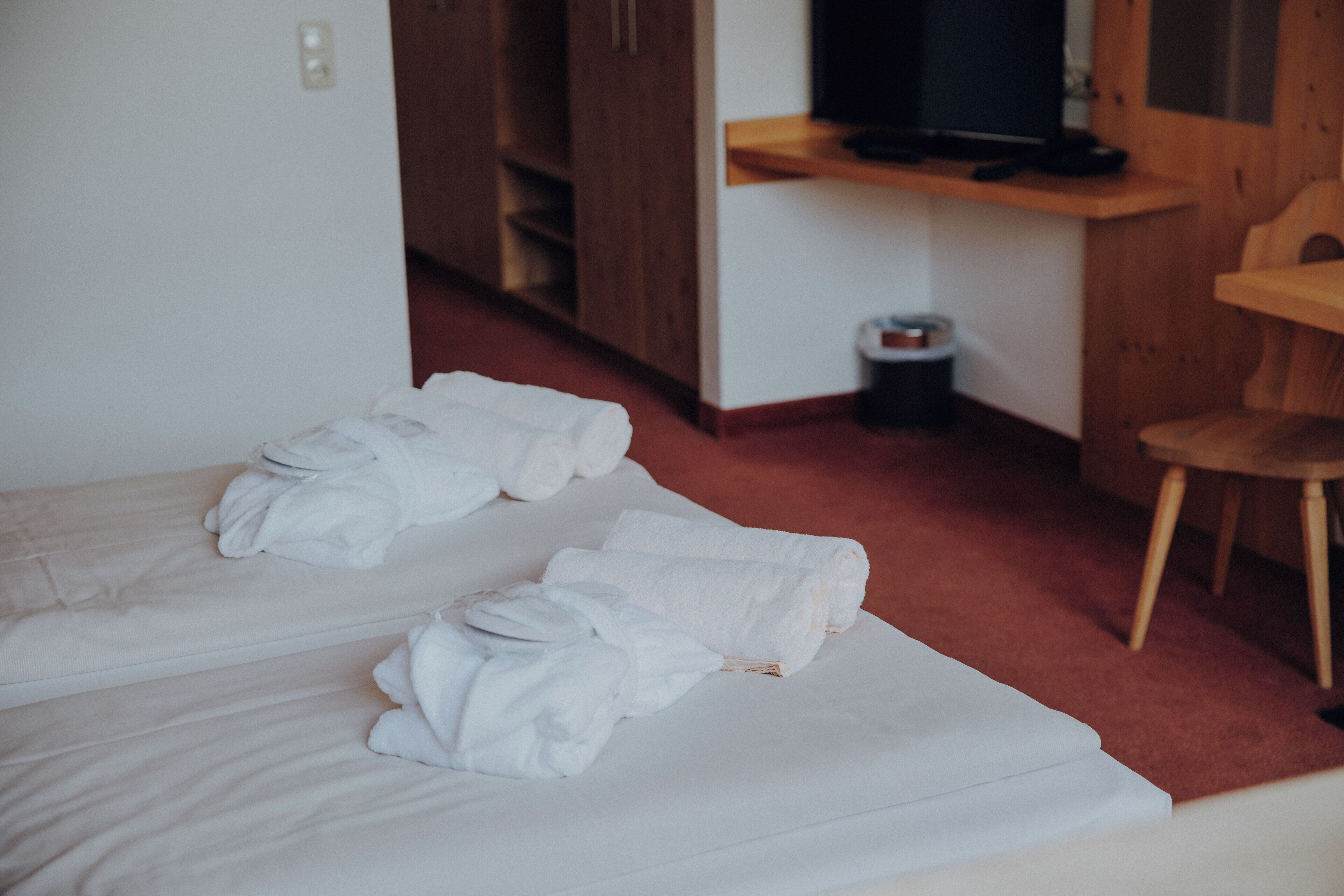 A hotel room with two beds, a wooden desk, and a television.