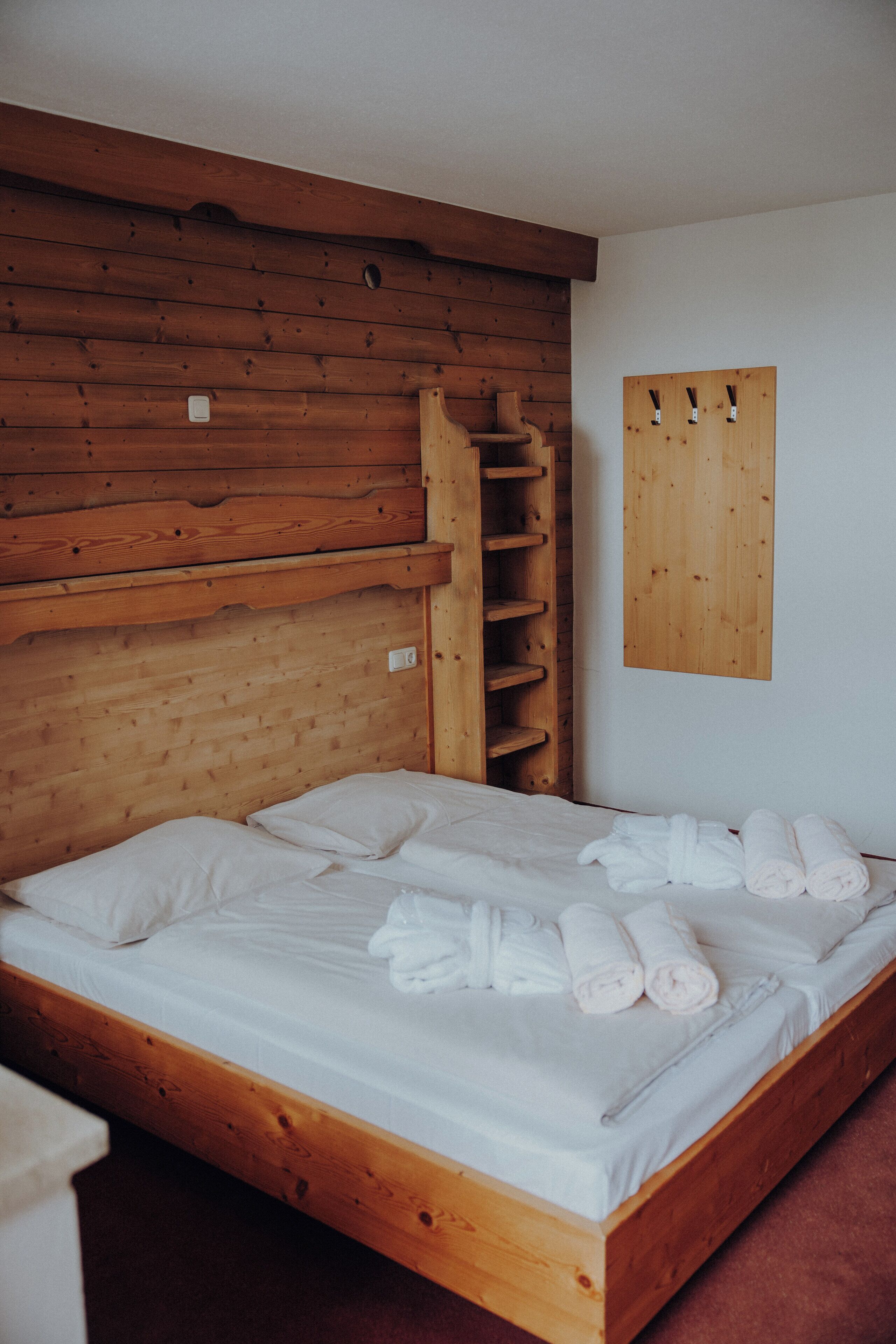 A wooden bunk bed with white bedding and towels.