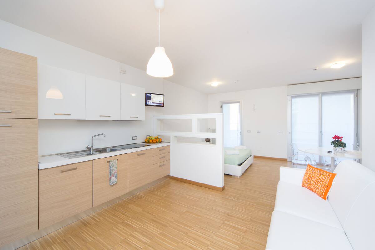 A modern kitchen with white cabinets, a wooden countertop, and a hanging pendant light.