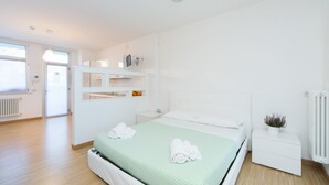 Ein modernes Hotelzimmer mit einem großen Bett, einem Nachttisch und einem eingebauten Kleiderschrank.
