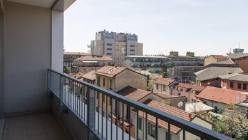 Un balcón con vistas a una zona residencial, que incluye varios edificios y un complejo de apartamentos alto.