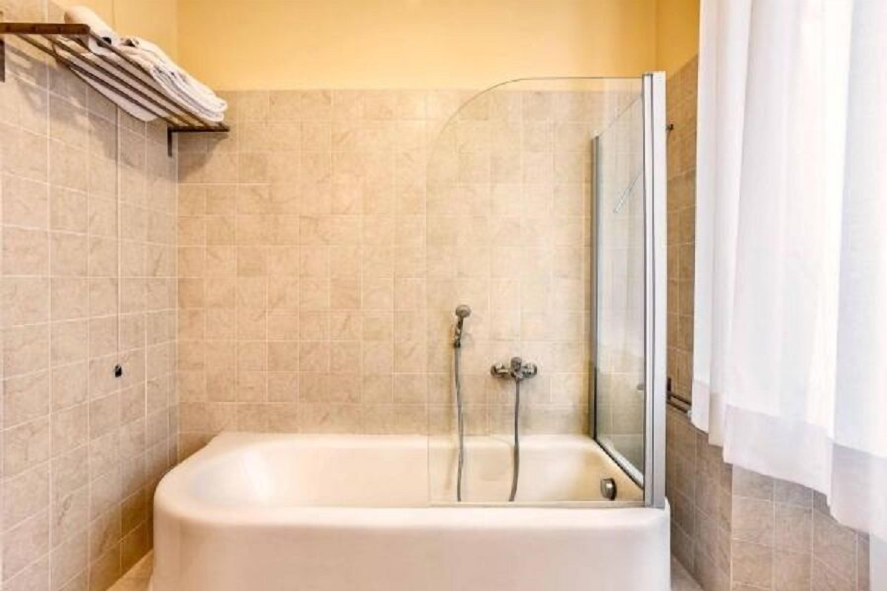 A bathroom with a bathtub, a glass shower enclosure, and a towel rack.