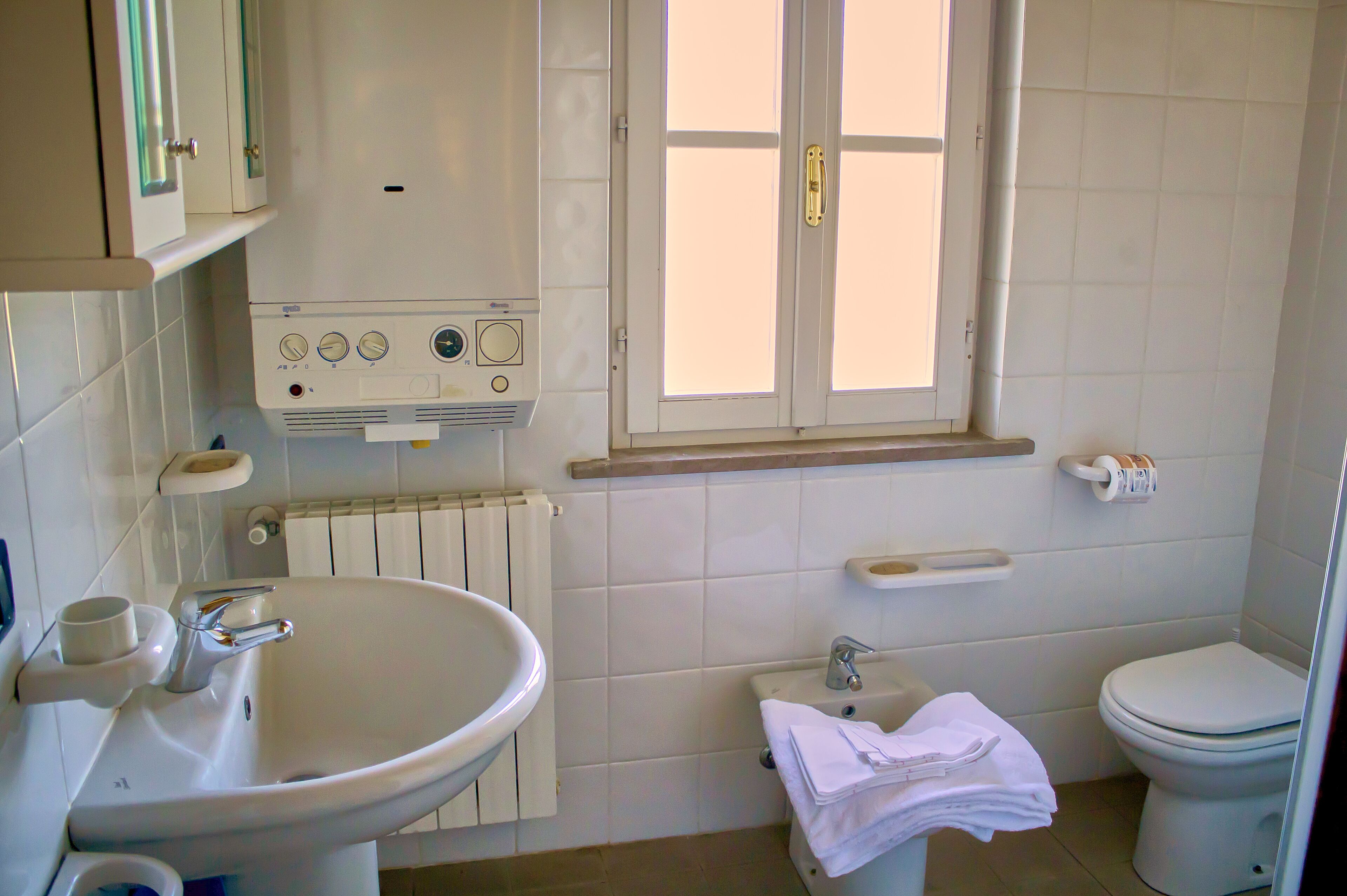 Ein Badezimmer mit Waschbecken, Toilette und Fenster.