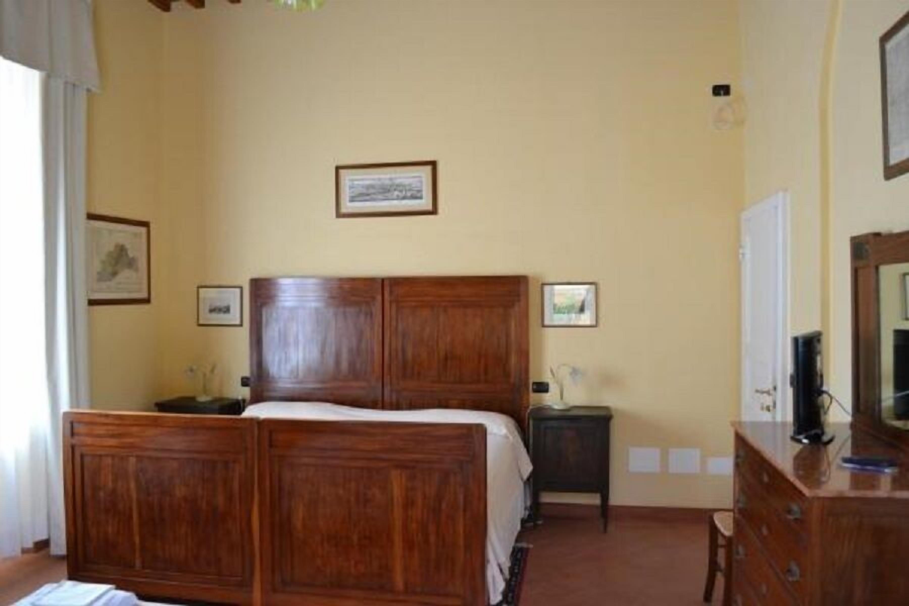 A bedroom with a wooden bed, bedside tables, and a dresser.