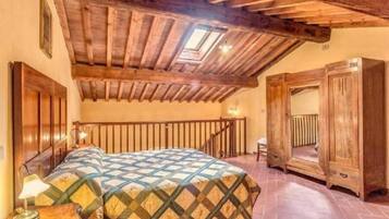 Una habitación con techo de madera, una cama con colcha estampada, una mesita de noche y una ventana con vistas.