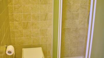 A bathroom with a toilet, a shower, and a towel rack.