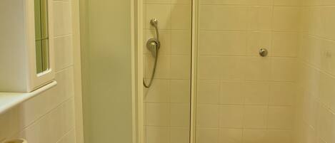 A bathroom with a shower, toilet, sink, and a mirror.