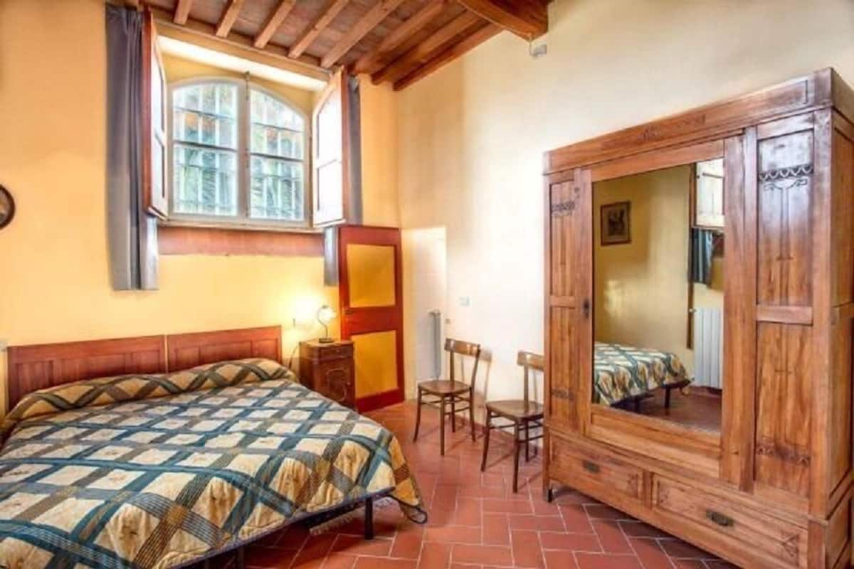 Ein Schlafzimmer mit einem Holzbett, einem Schrank aus Holz, einem kleinen Tisch und einem Stuhl.