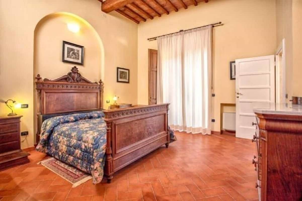 Ein Schlafzimmer mit einem hölzernen Bett, einem Nachttisch, einer Kommode und einem Fenster mit Vorhängen.