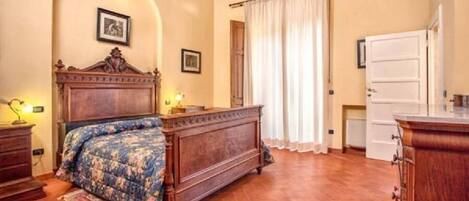 A bedroom with a wooden bed, a nightstand, a dresser, and a window with curtains.