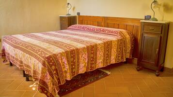 A bedroom with a large bed, wooden headboard, two bedside tables with lamps, a nightstand, and a wooden wardrobe.