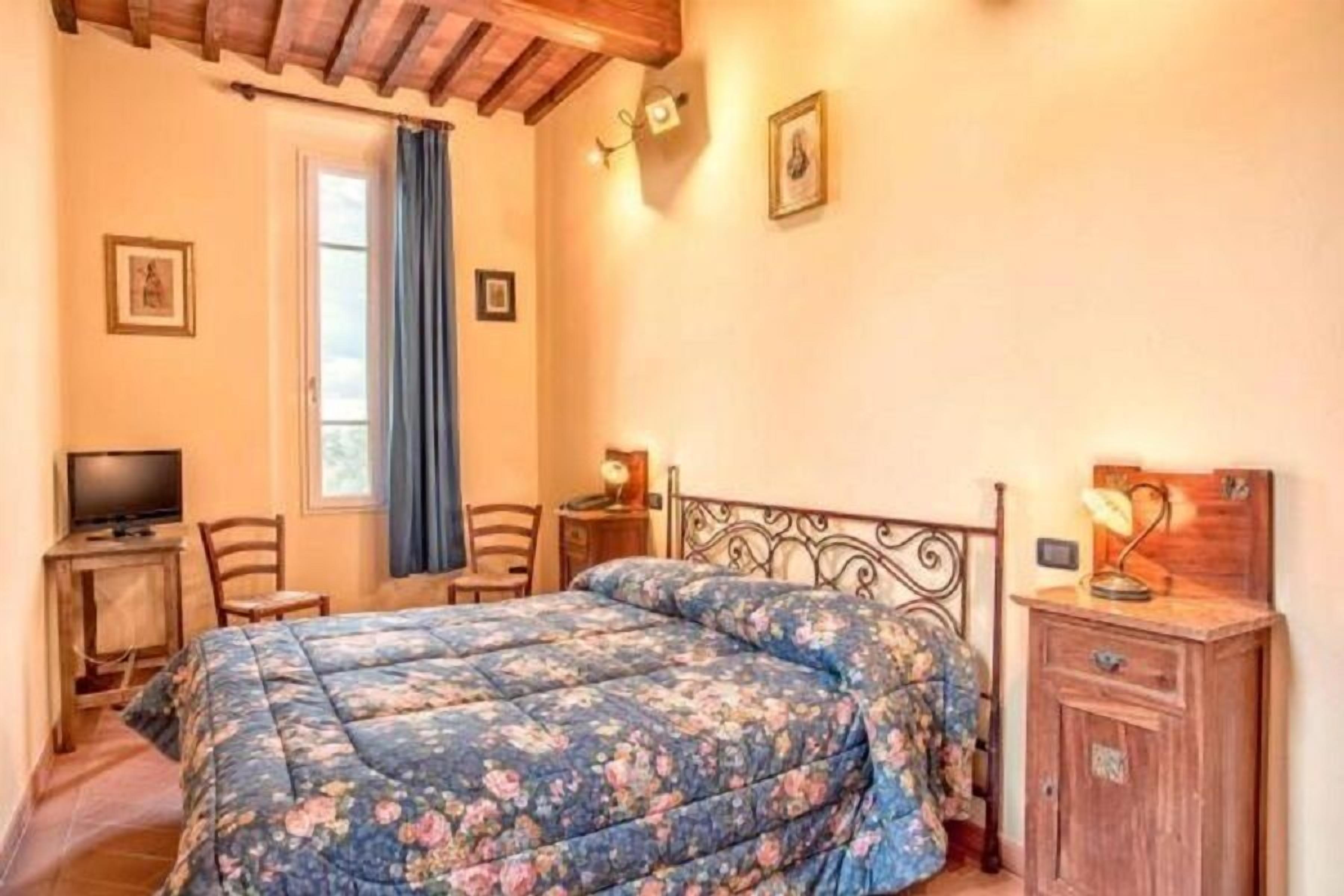 Una camera da letto con un letto, una scrivania, una sedia, una TV e un armadio.