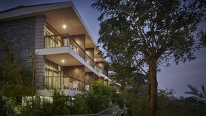 A multi-story building with balconies, surrounded by trees and a bridge. - Ragamaya Resort & Spa Munnar (Udumbanchola)