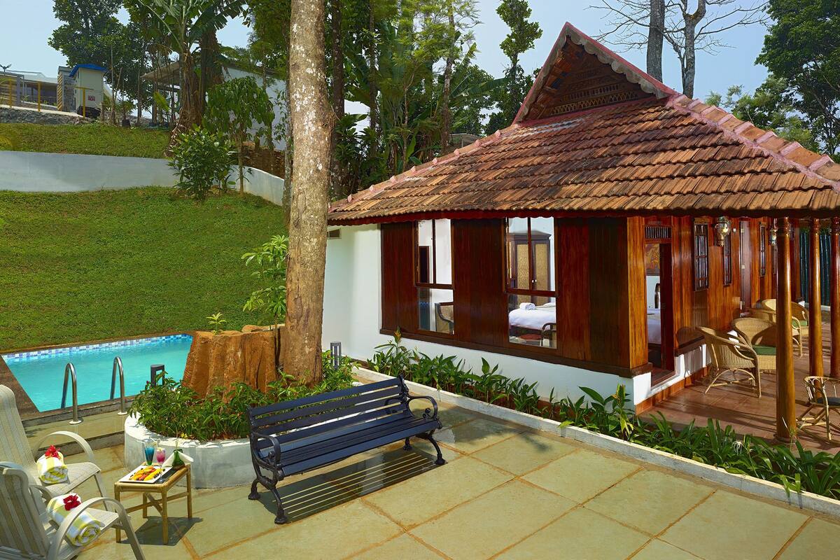 A poolside area with a wooden deck, a bench, and a small pavilion with a tiled roof.
