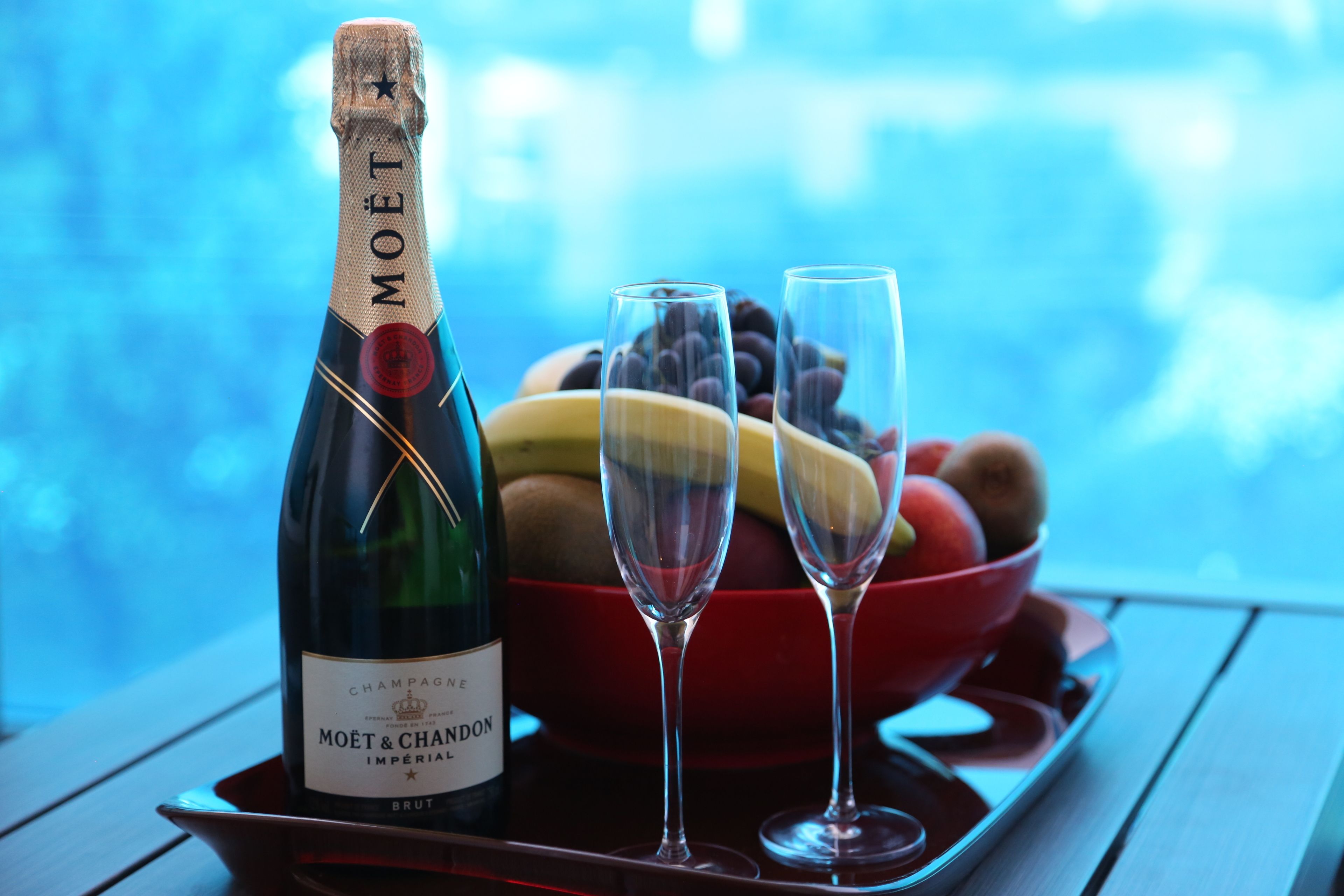 Une bouteille de champagne Moët & Chandon, deux verres et un saladier de fruits sur un plateau.