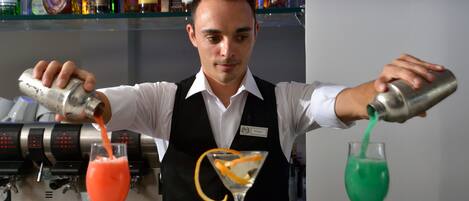 A bartender pouring drinks into martini glasses.