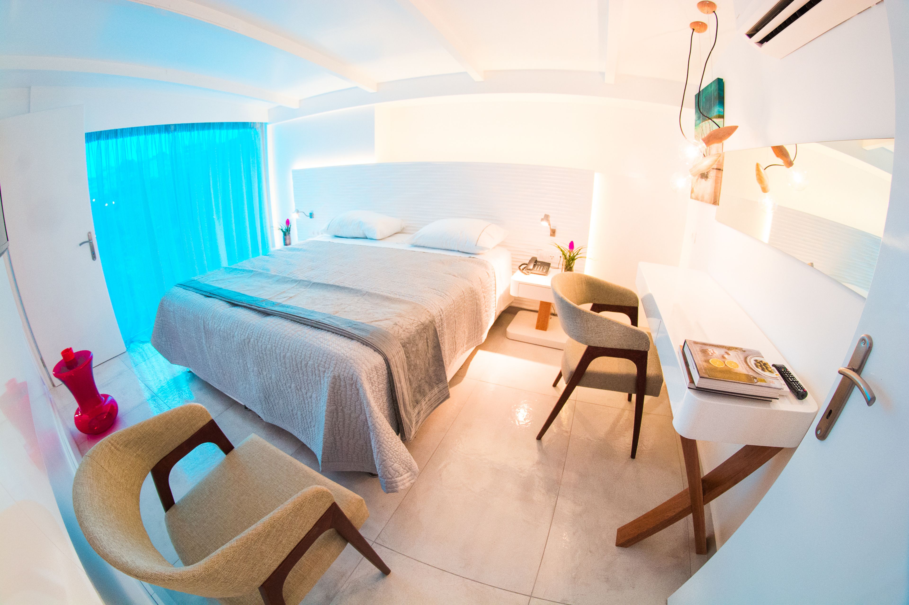 A modern bedroom with a large bed, a desk, and a chair.