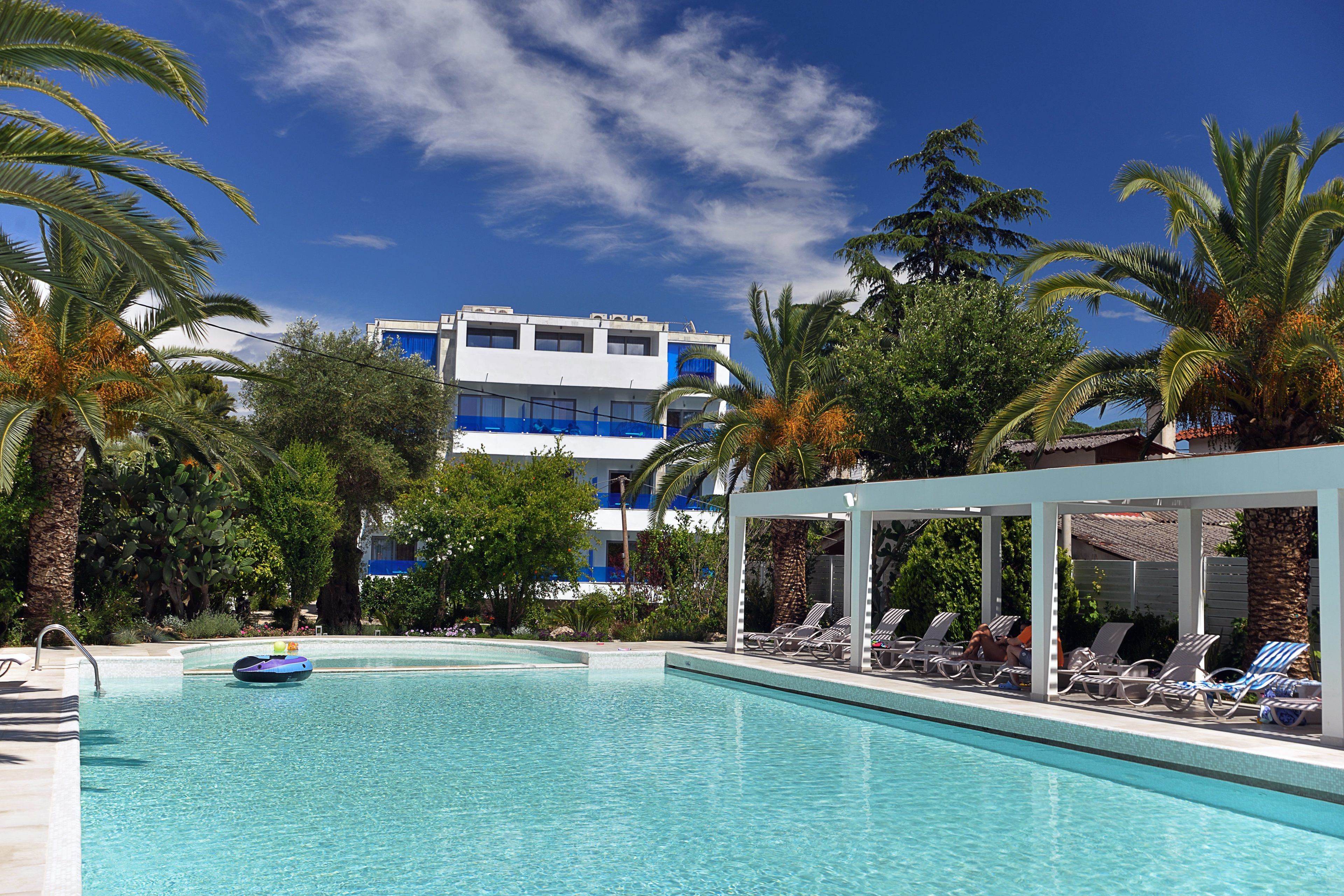 Una piscina con sillas de descanso y palmeras.