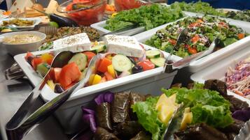 Buffet amb diferents plats, incloent amanides, verdures i una selecció de salses.