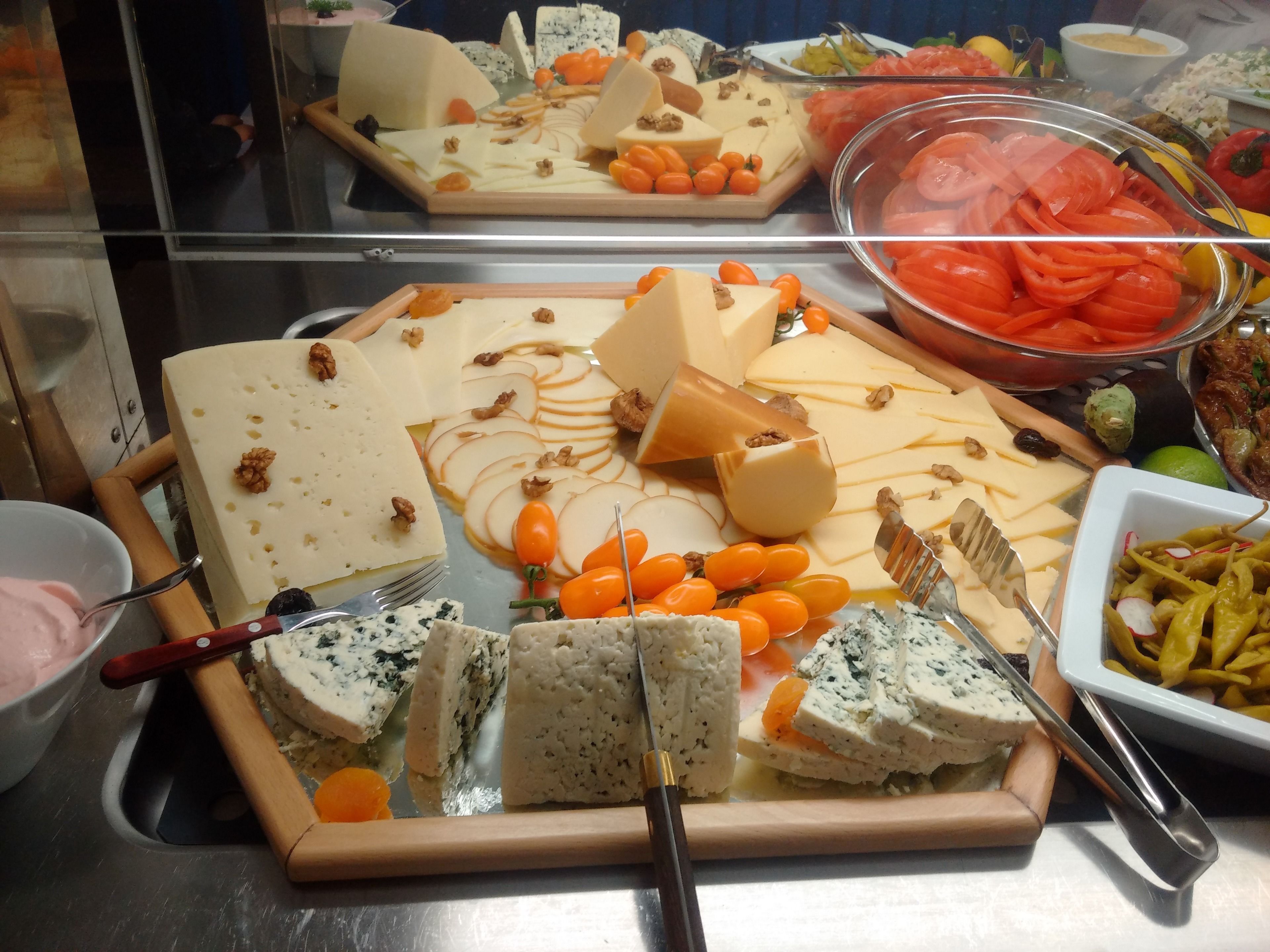 A buffet with various cheeses, fruits, and vegetables.