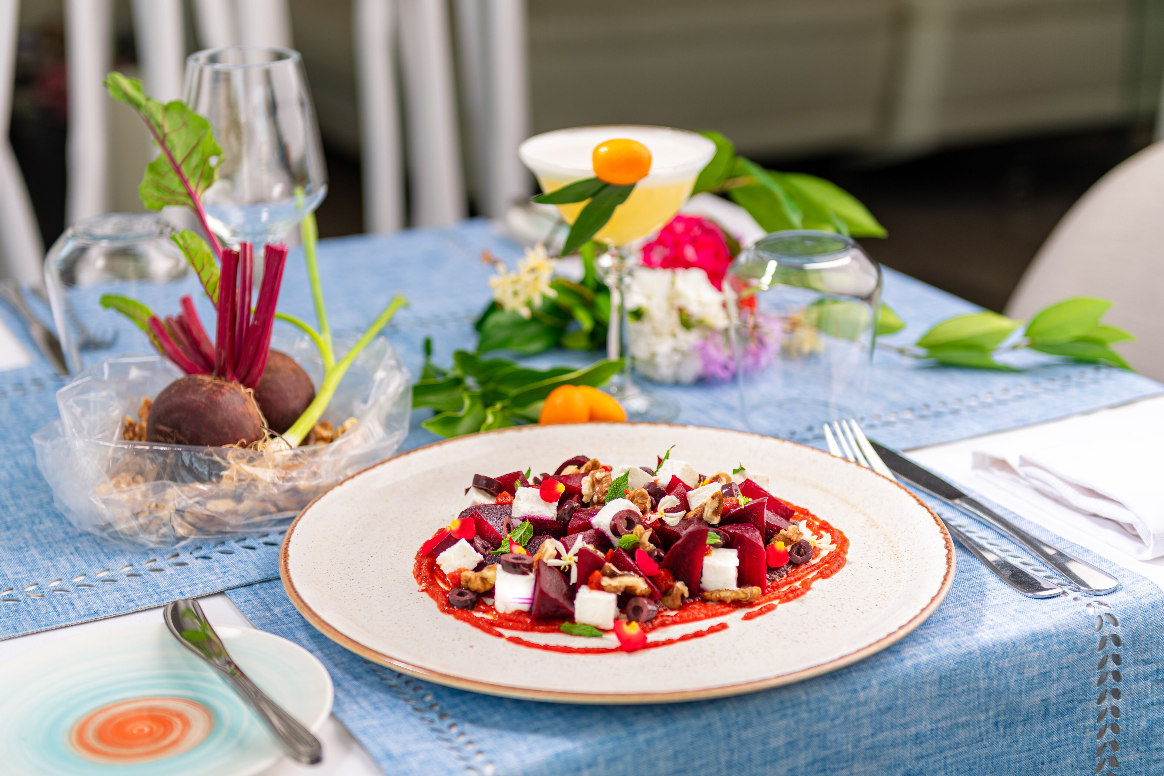 Une table dressée avec une assiette de nourriture, un verre d’eau et un verre de jus de fruits.